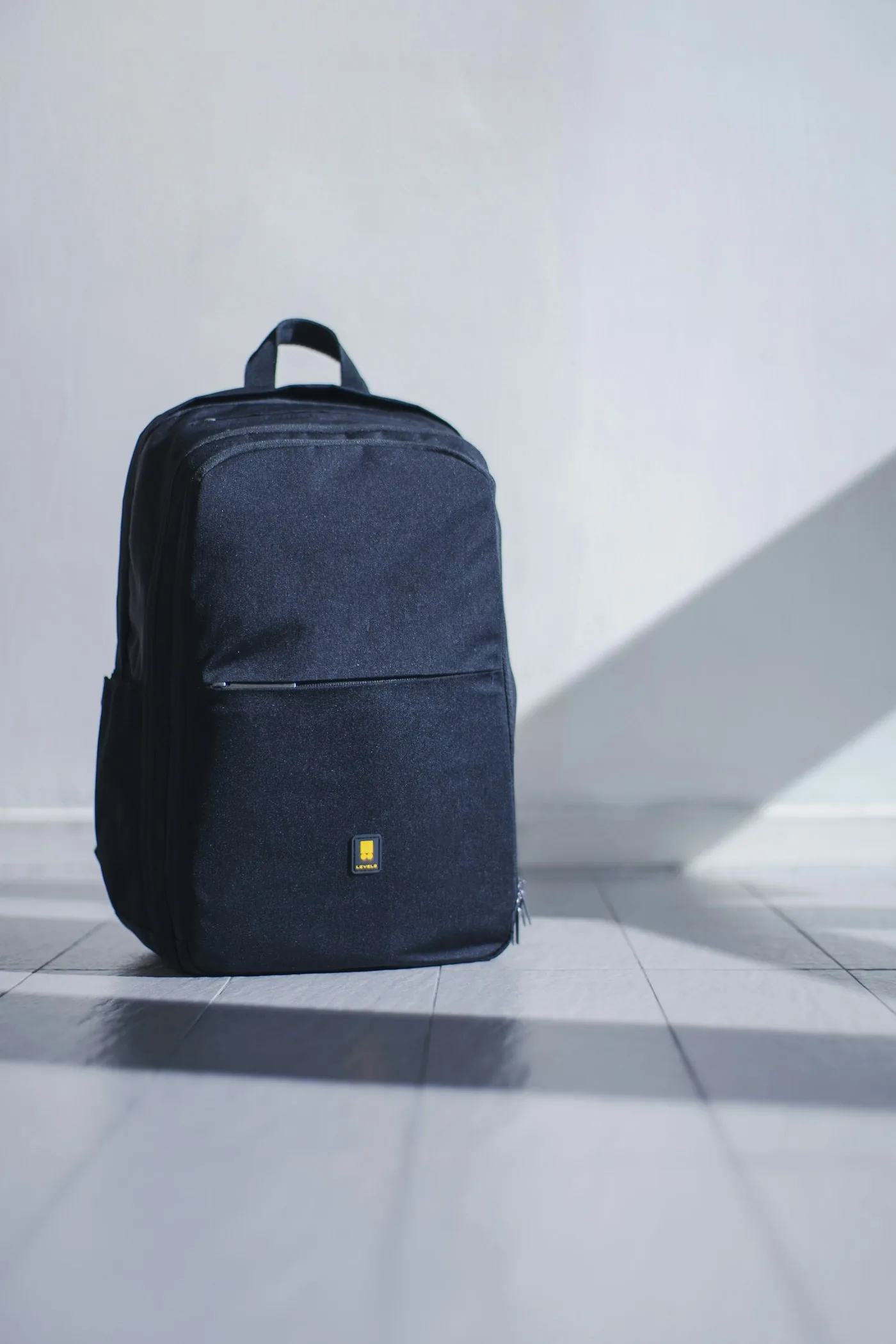 Dark backpack resting against a pale wall
