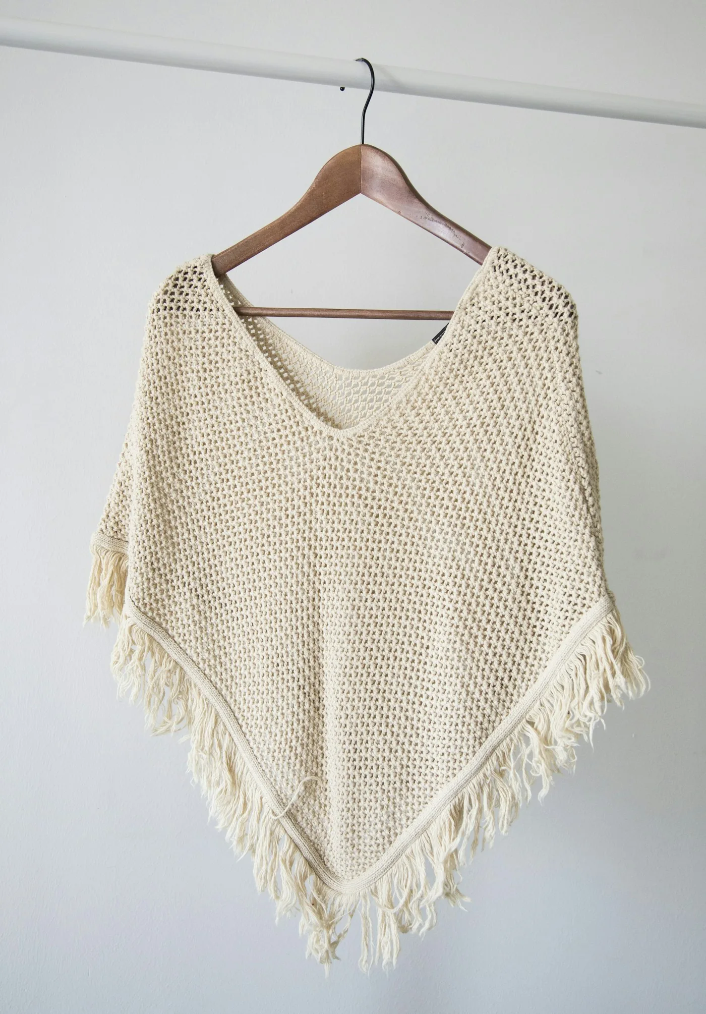 Cream knitted garment with fringe on a rail